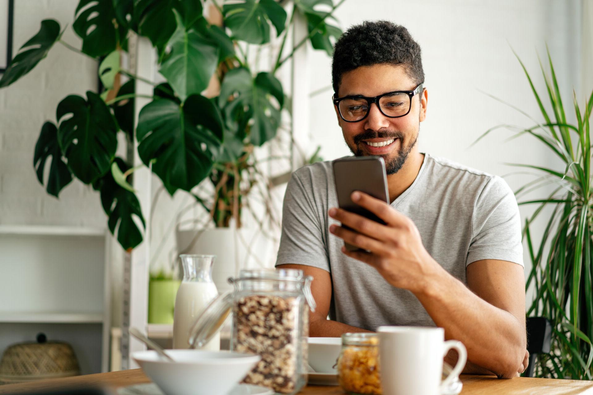 A young man checks his savings account on his mobile phone.